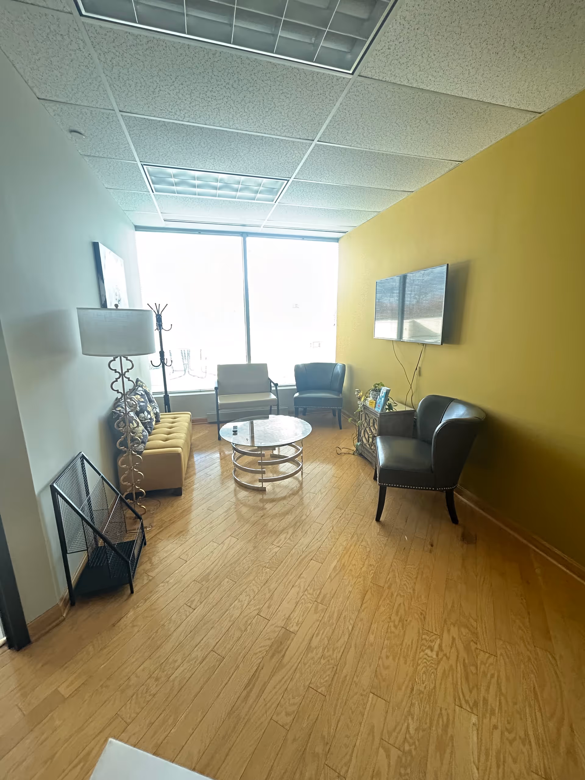 Lounge area with chairs, sofa, coffee table, and a wall-mounted TV.