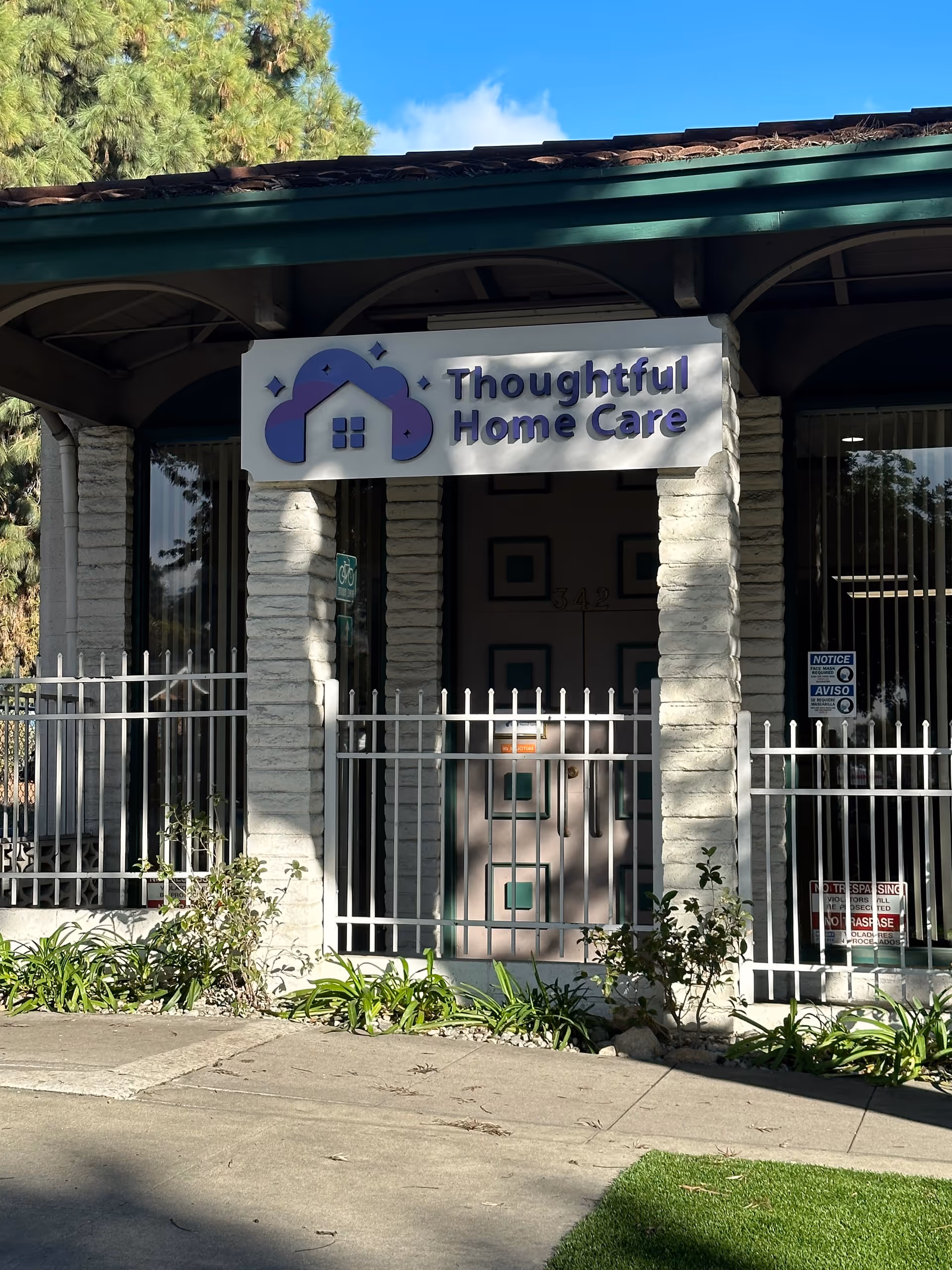 Front entrance of Thoughtful Home Care with gated doorway, stone columns, and signage.