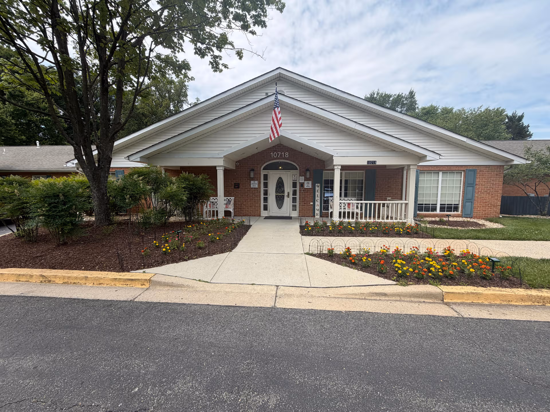 Exterior of Arden Courts Potomac senior living facility, with brick facade, flag, and landscaped front yard.