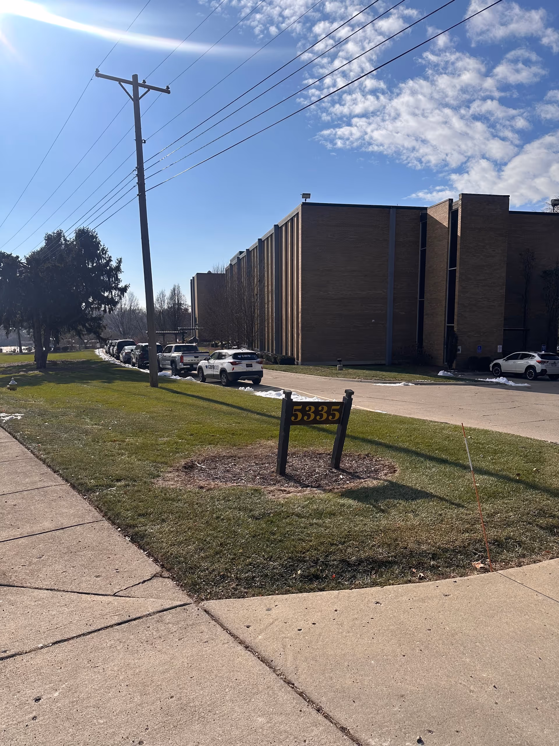 Exterior view of a brick senior care facility with parked cars and a 5335 address sign.