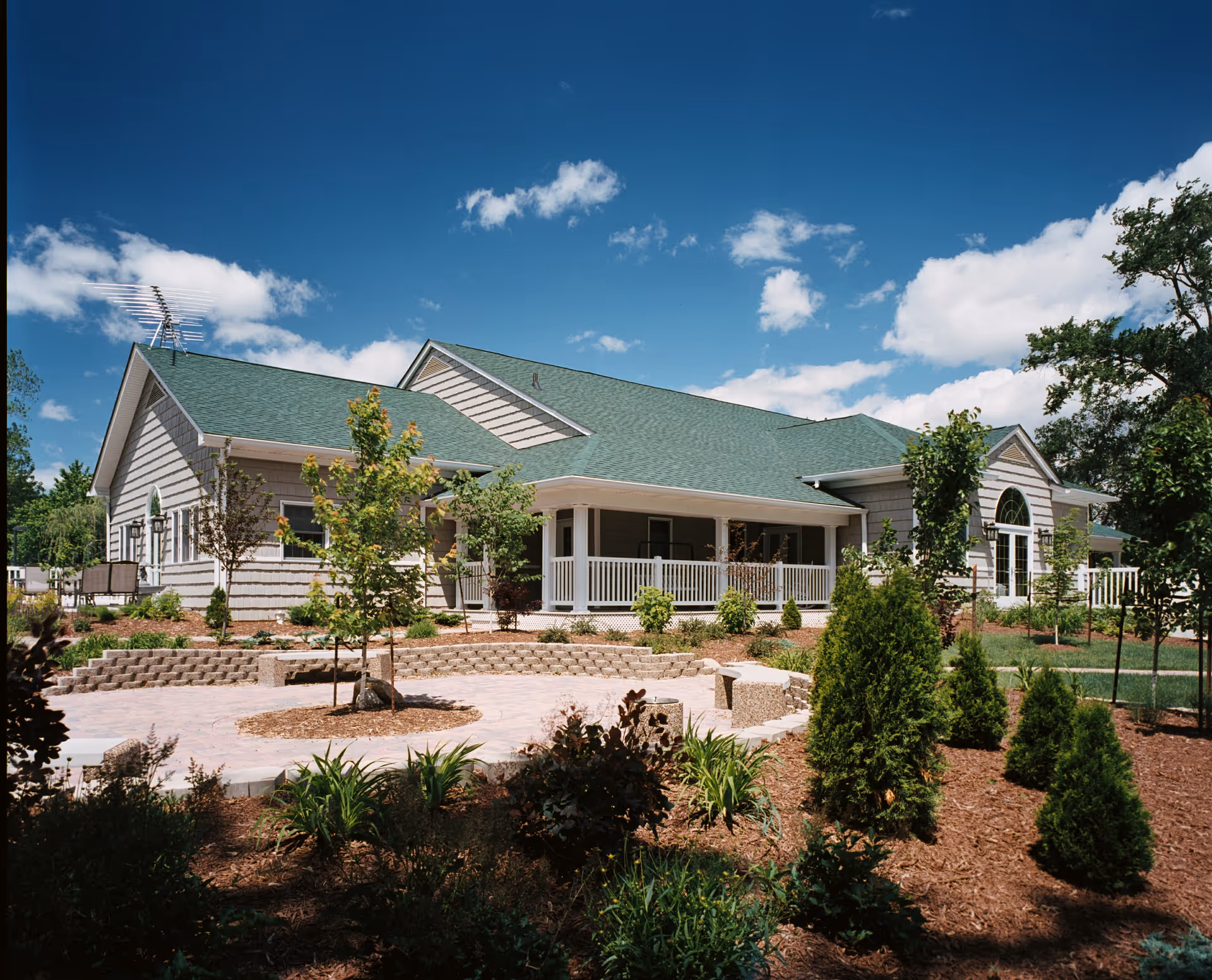 Single-story hospice building with a green roof, front porch, and landscaped grounds.