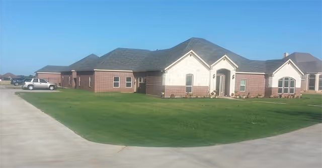 Exterior view of Anchor Way Senior Care, a single-story brick facility with lawn and driveway.