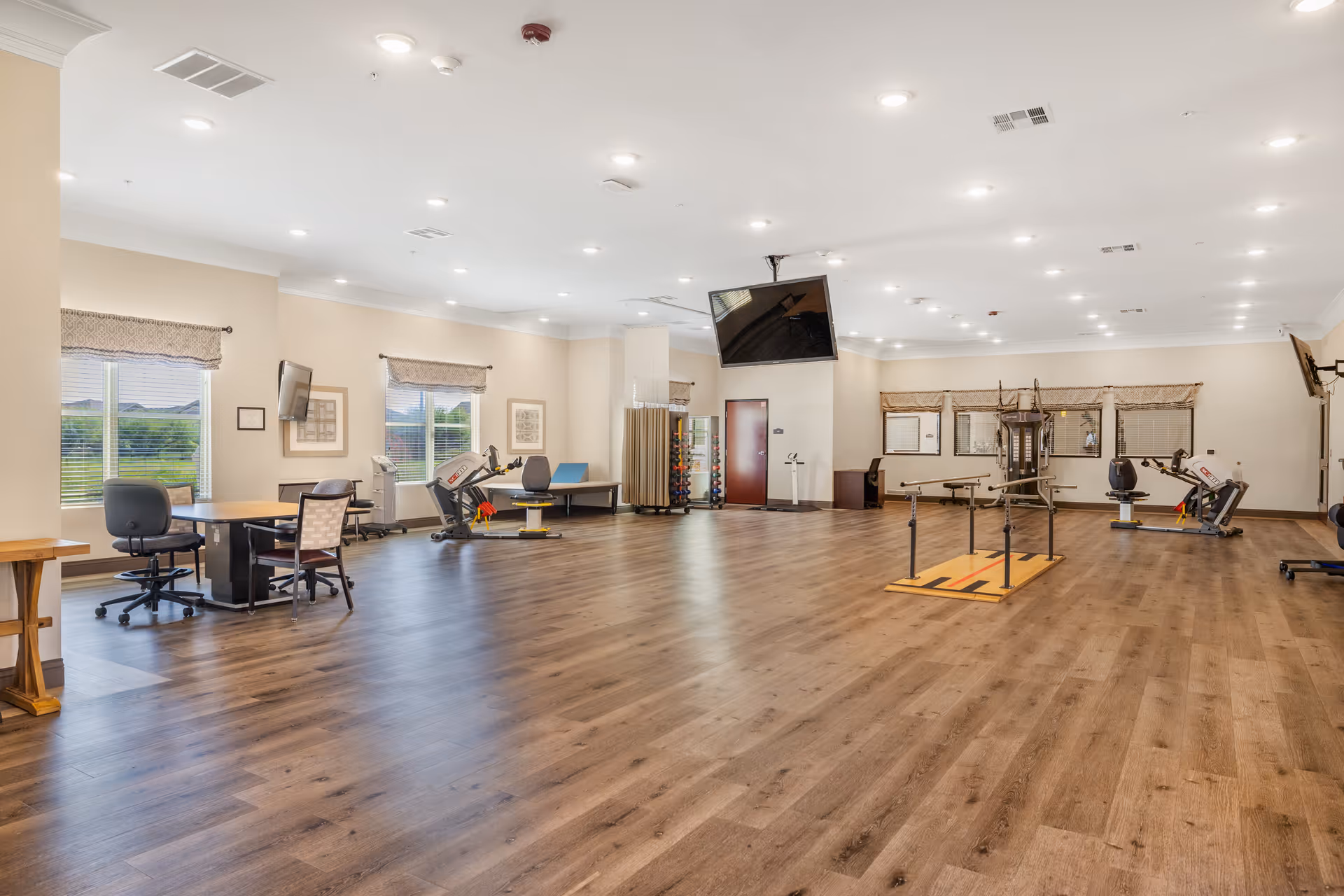 Spacious indoor fitness area with exercise machines, seating, and a mounted TV.