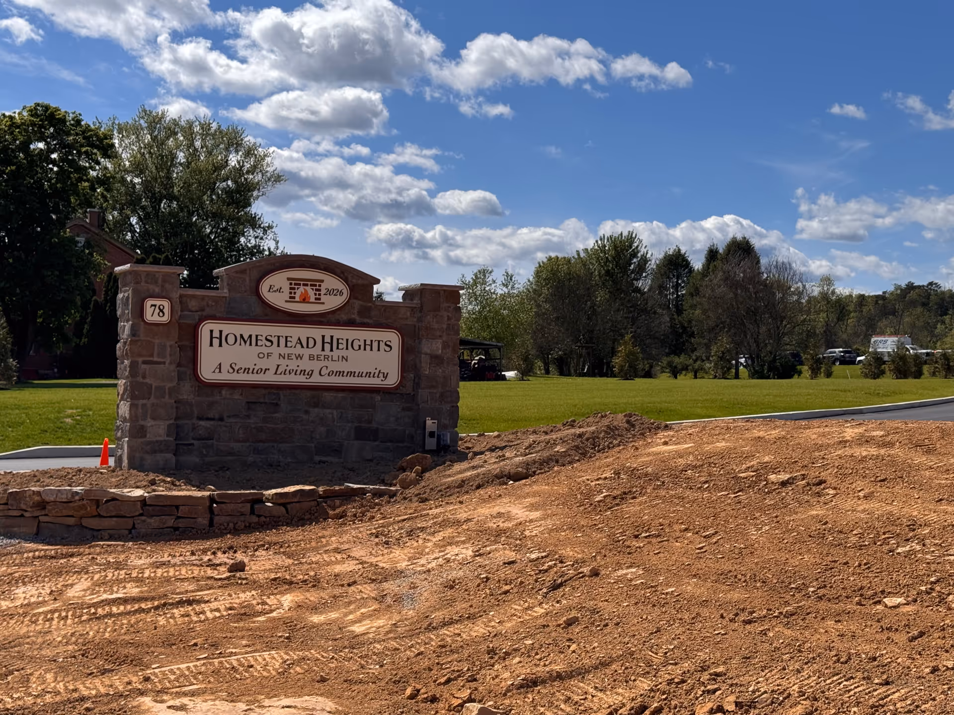 Stone entrance sign reads Homestead Heights of New Berlin, a senior living community, beside a lawn.