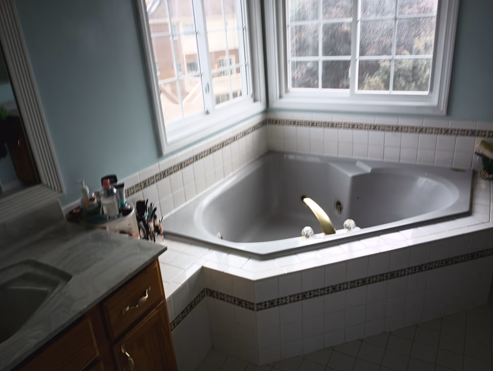 Bright bathroom with a corner bathtub, tile surround, and a large window above.