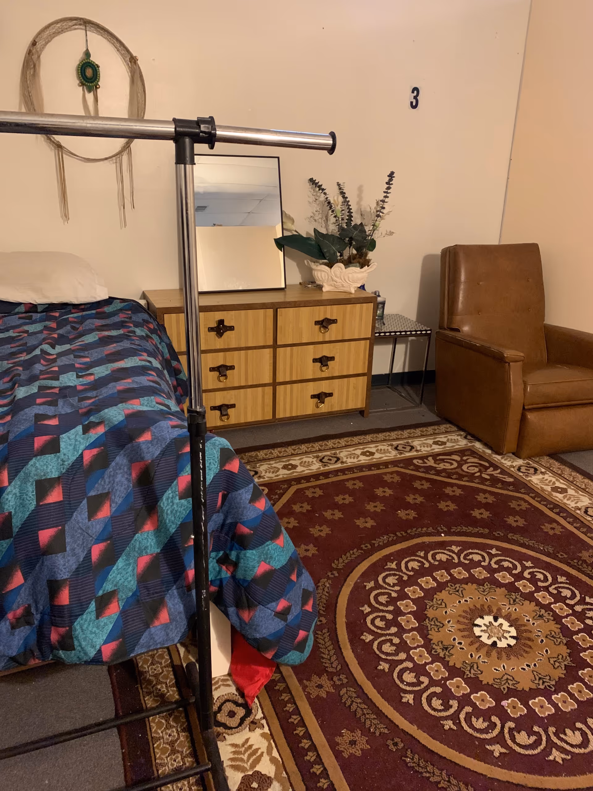 Bedroom in Verna's House with a bed, dresser, mirror, chair, and patterned rug.