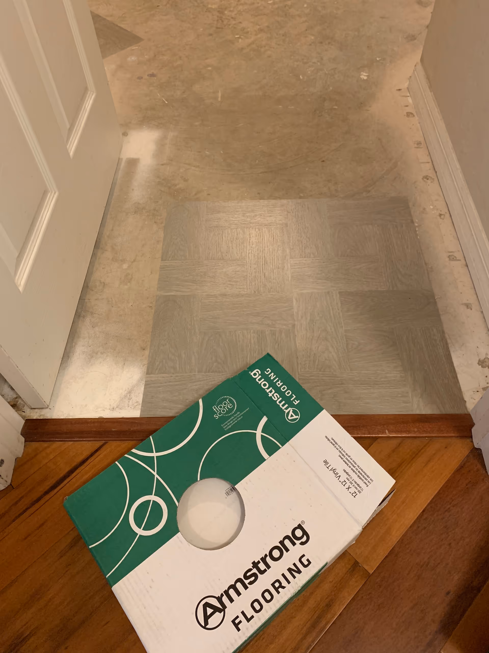 Indoor doorway with new gray flooring tiles and an Armstrong Flooring box.
