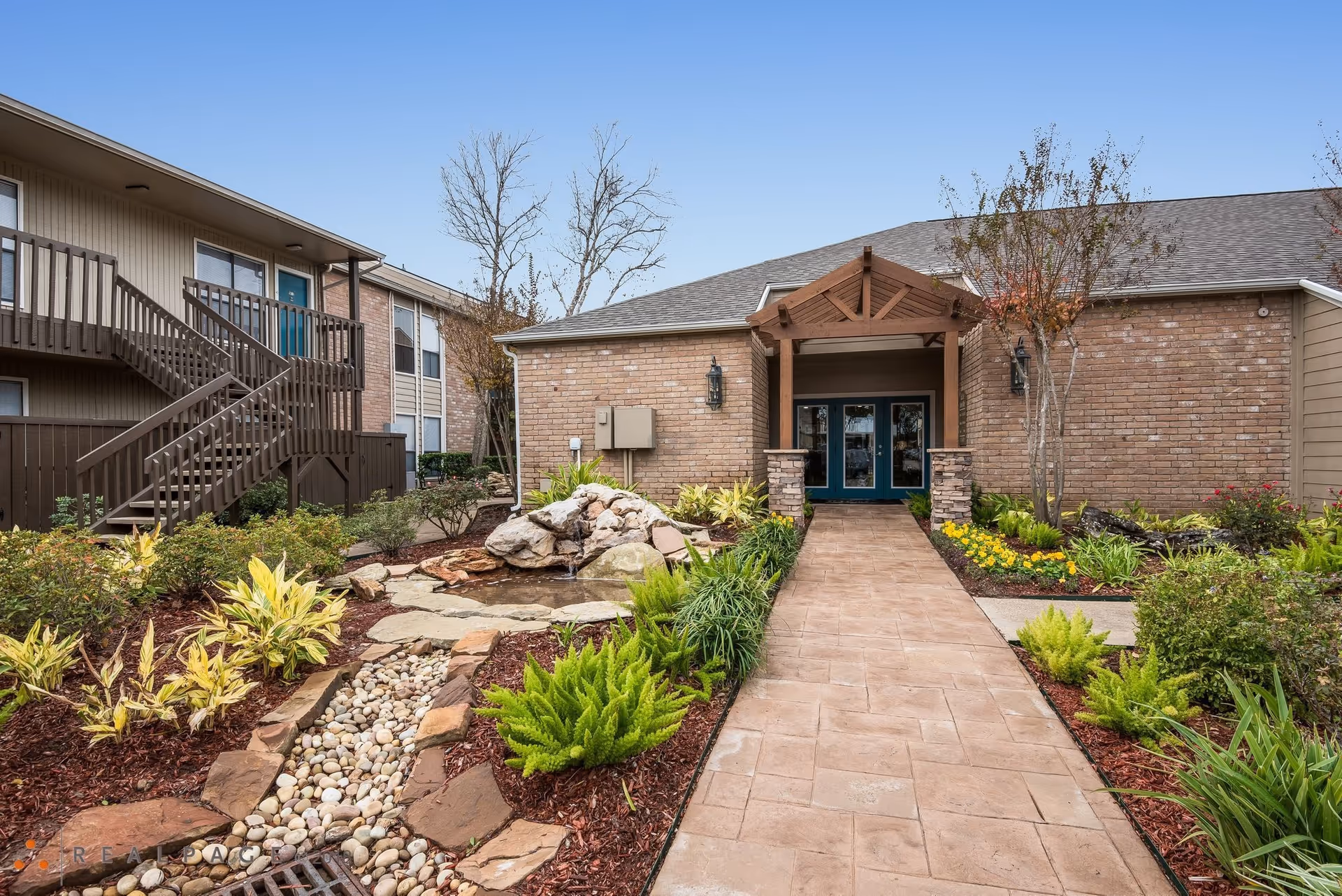 Braesridge Apartments exterior entrance with brick facade, covered porch, and landscaped walkway.