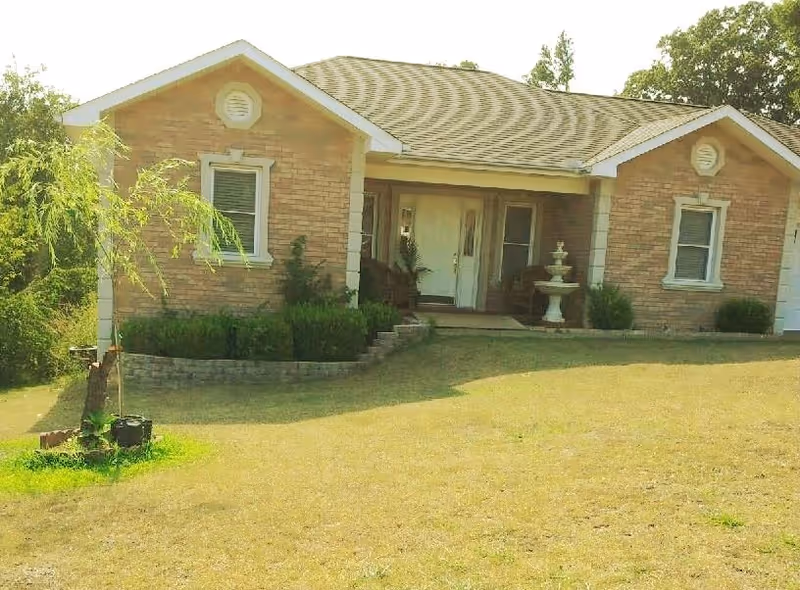 Exterior view of a single-story brick assisted living facility with front entrance and steps.