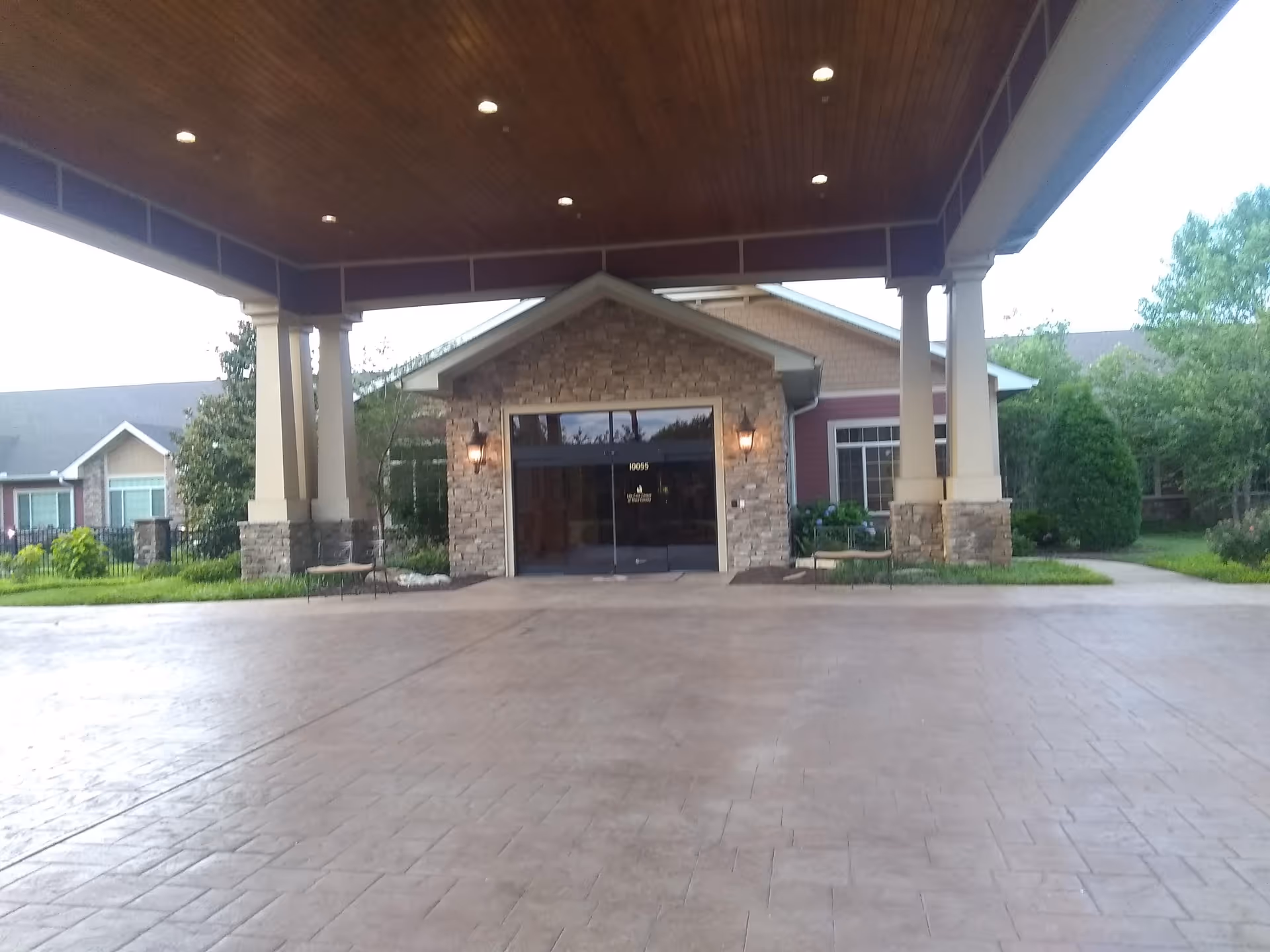 Covered entrance with stone facade and glass doors at the facility's front.