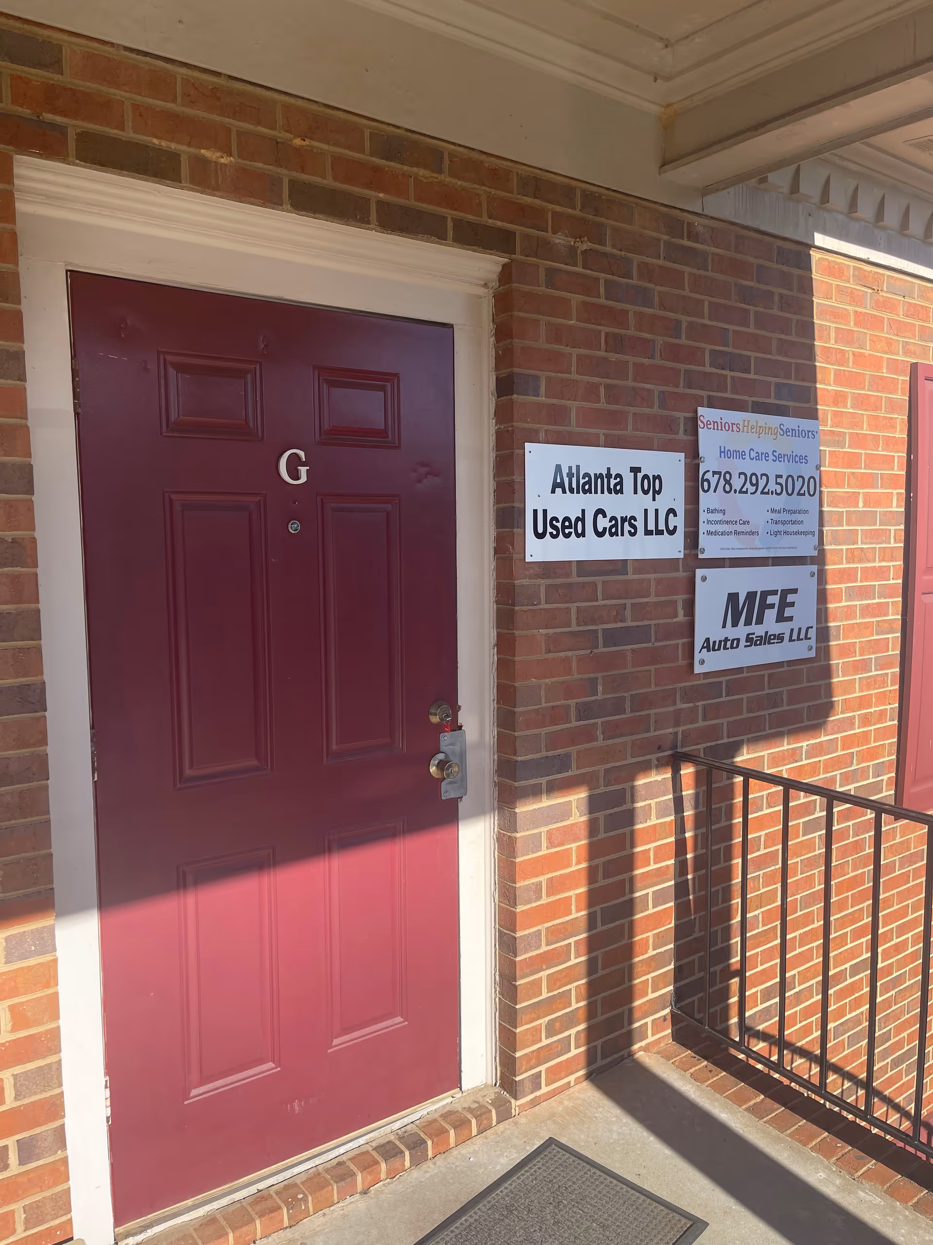 Brick exterior building with maroon front door and signs on wall
