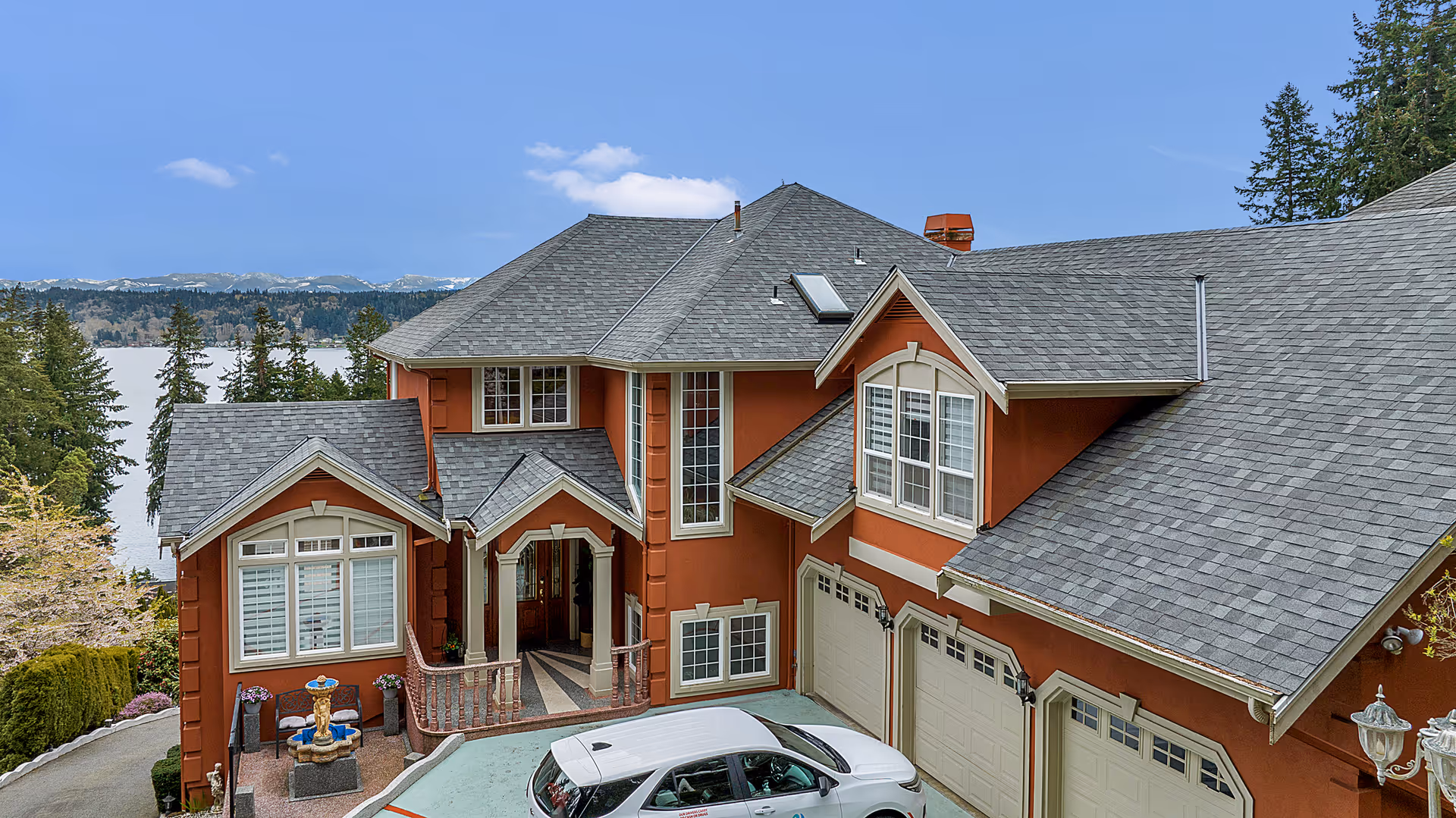 Two-story orange stucco senior living facility with front entrance, driveway, and lake view.