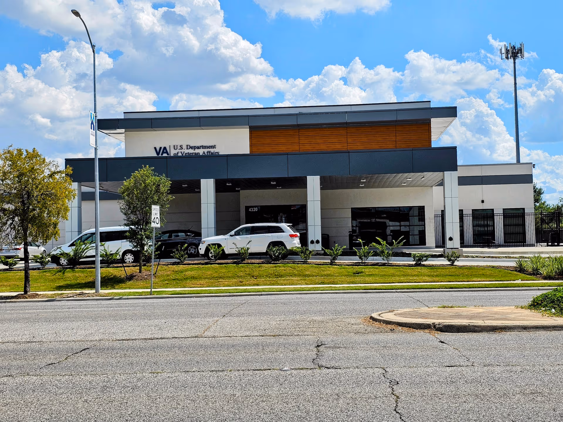 Front view of a modern VA facility exterior with parked cars and blue sky.