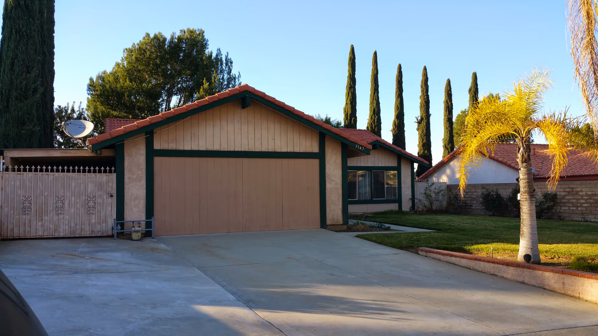 Front exterior of Mountain View Cottages - I with garage, driveway, and palm-lined lawn.