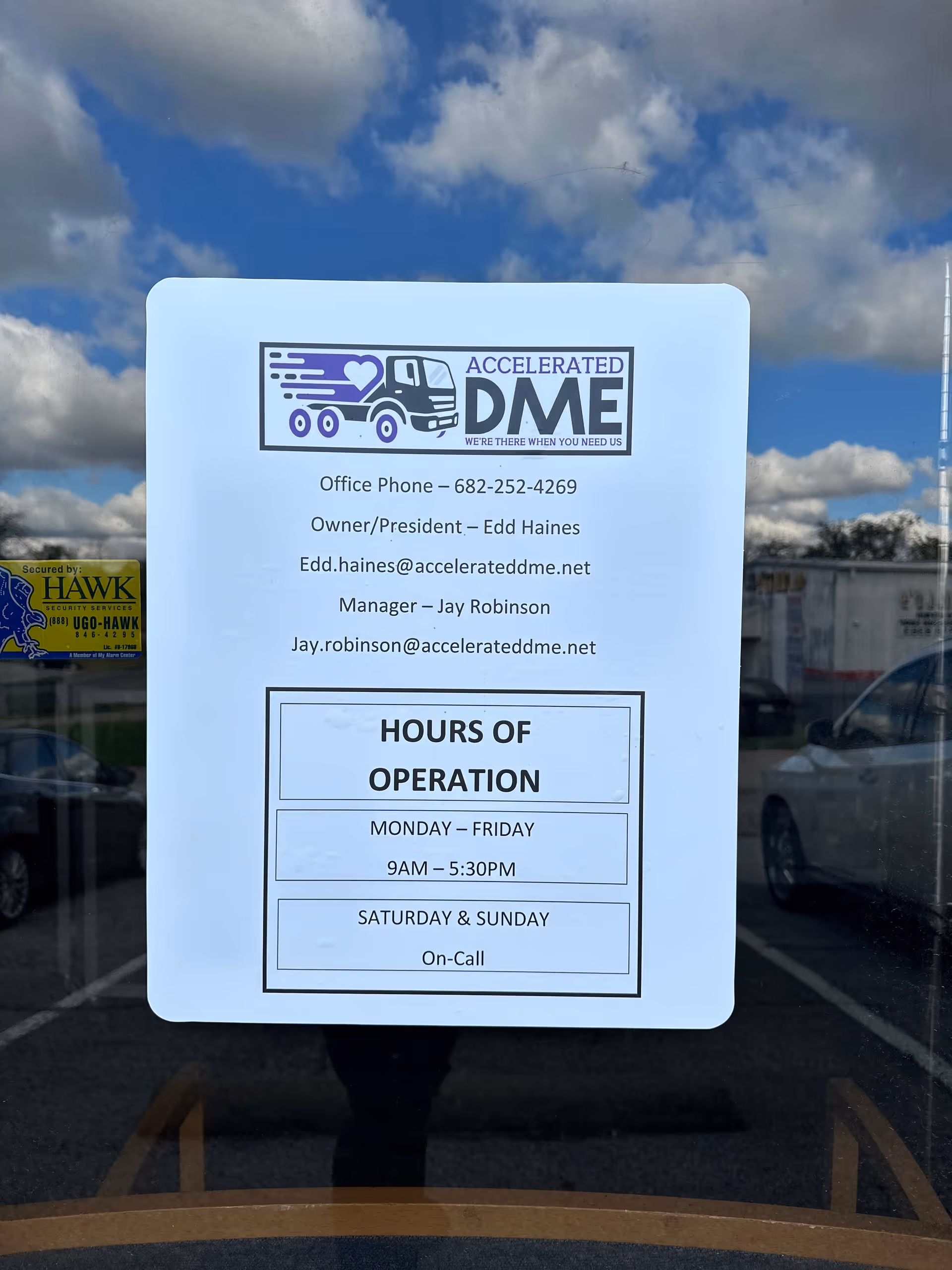 Sign on a glass door for Accelerated DME displaying hours and contact details.