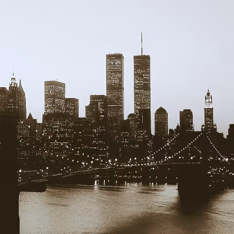 Sepia-toned city skyline with a lit bridge spanning a river at dusk