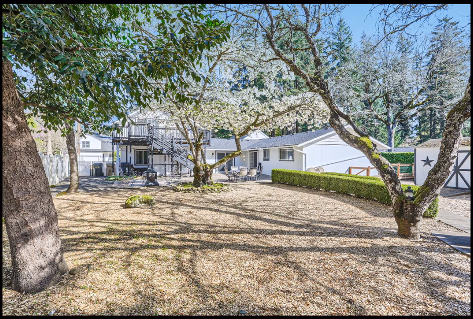 Outdoor yard at Oswego Cottage with trees, gravel ground, and patio furniture.
