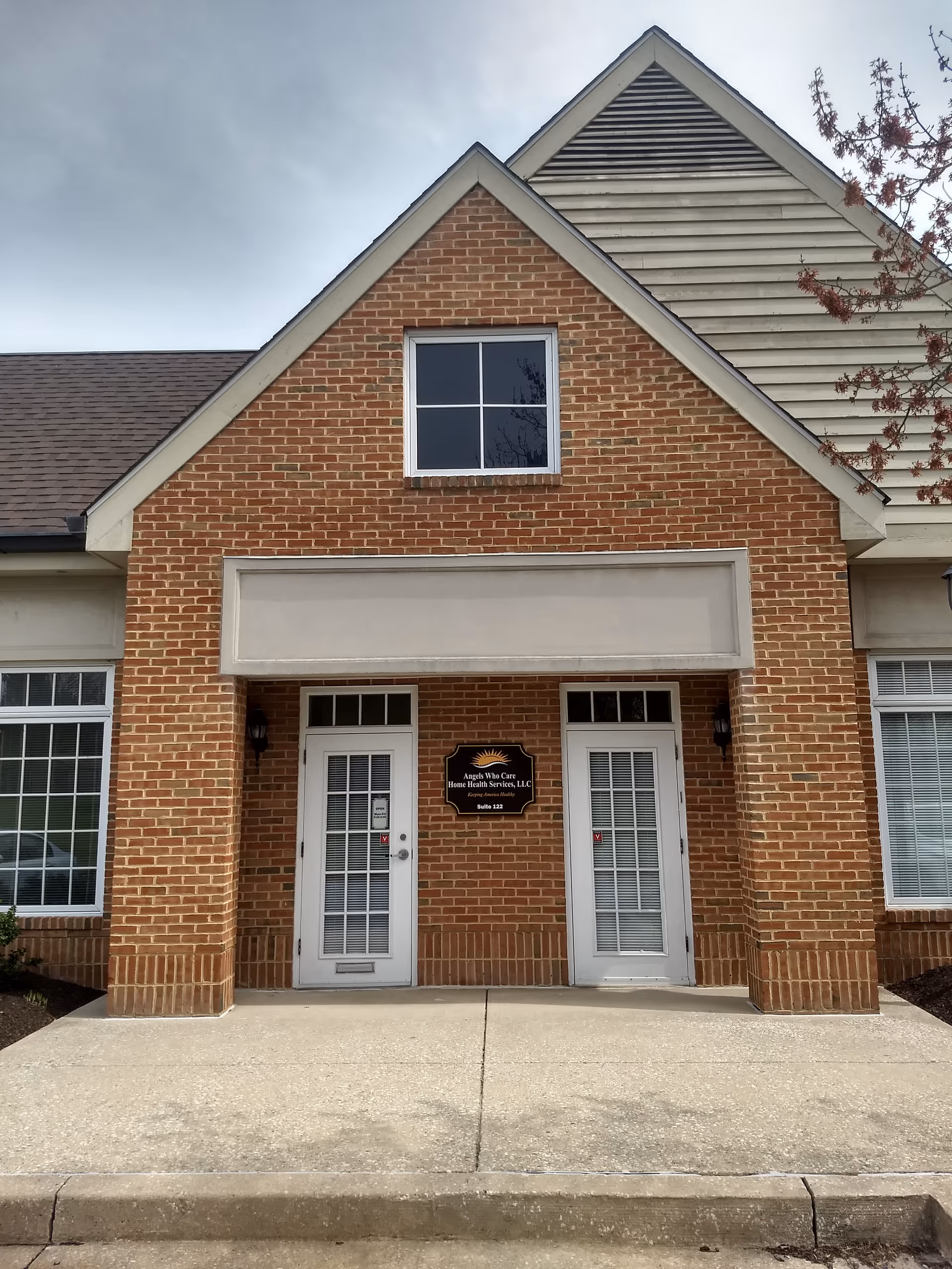 Brick building facade with two white doors and a centered sign above the entrance.