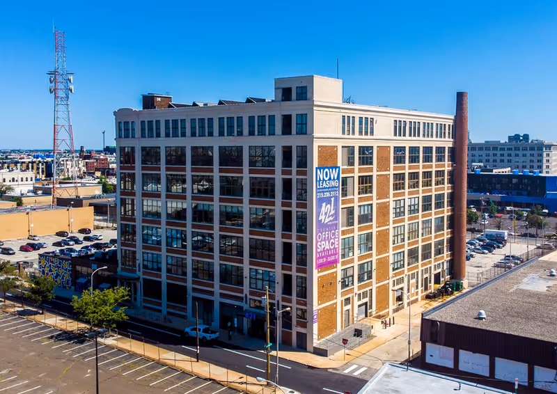 A modern multi-story brick office building with a Now Leasing banner