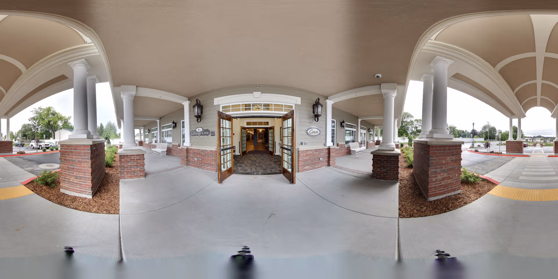 Panoramic view of Carriage Cove's covered front entrance with columns and brick accents.