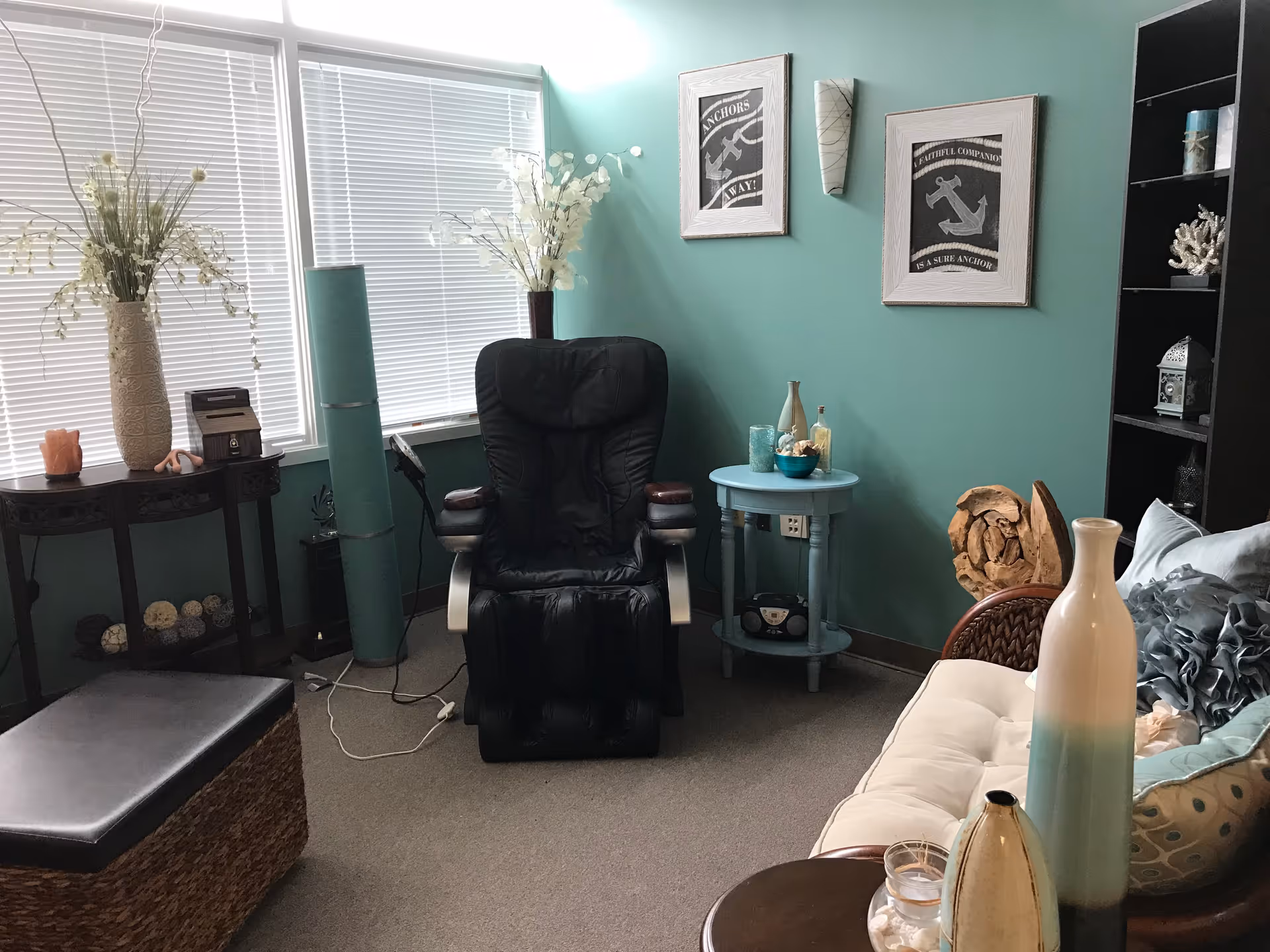 Teal-walled living room featuring a black recliner, couch, and decorative shelving.