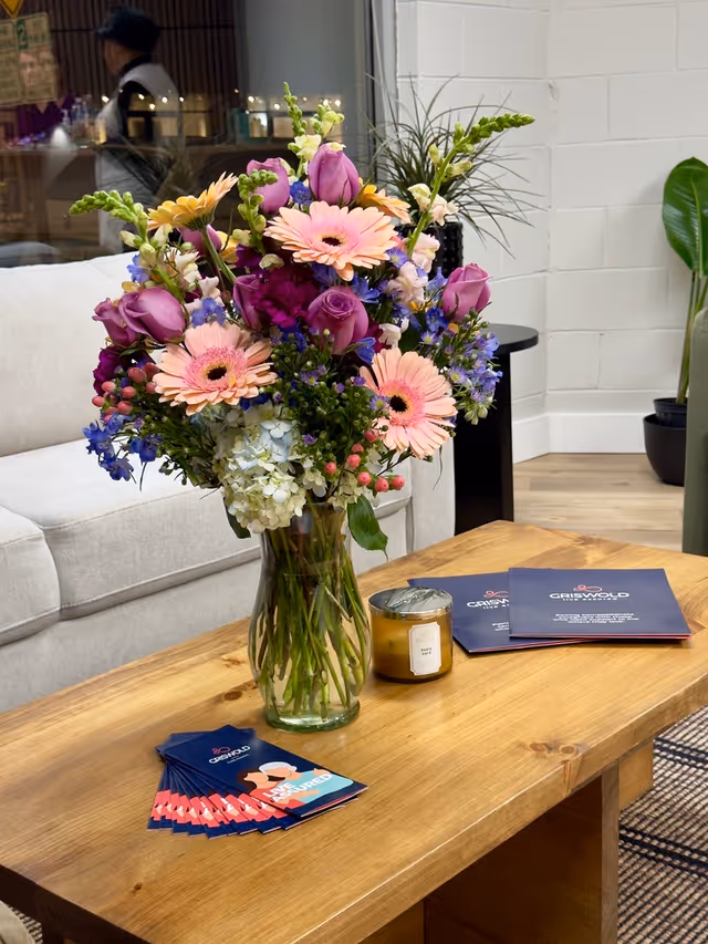 A vibrant bouquet in a glass vase on a wooden coffee table.