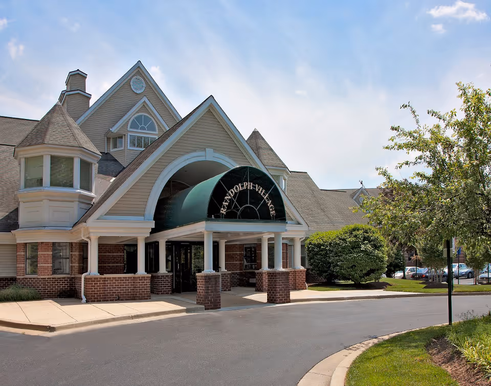 Front view of Randolph Village senior living facility with arched entrance and brick columns.