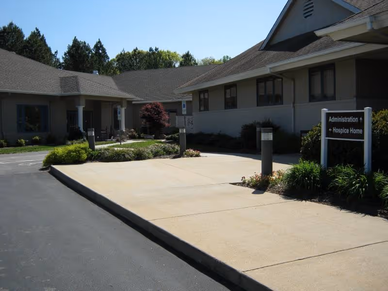 Exterior view of Ancora Compassionate Care facility front with driveway and sign.