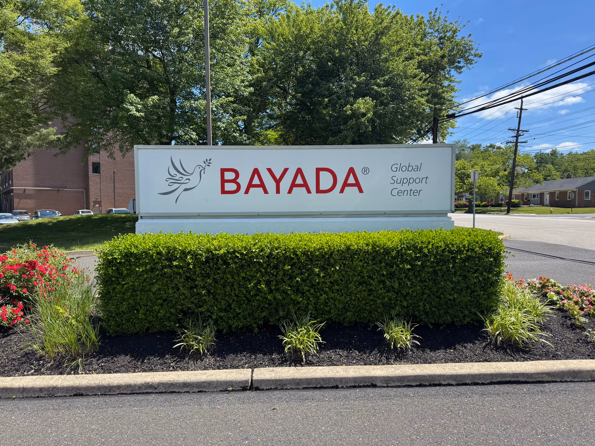 Exterior sign reading BAYADA Global Support Center surrounded by trimmed hedges and flowers