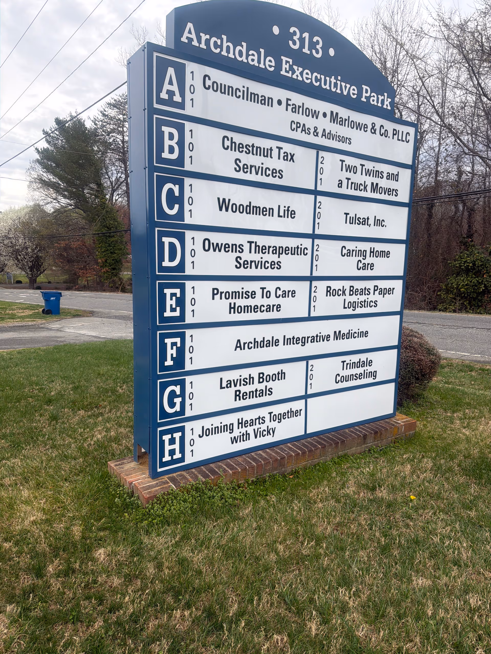 Tall blue-and-white external directory sign listing Promise To Care Homecare among tenants.