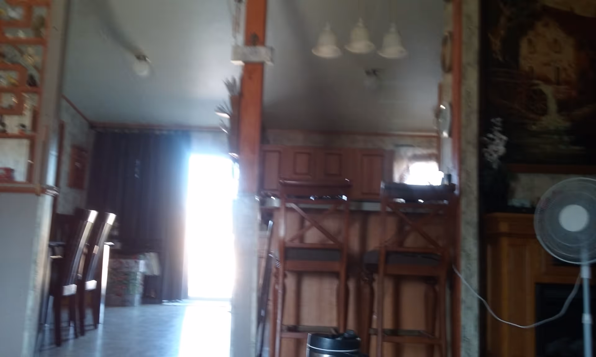 Blurry interior of a cozy dining/kitchen area with bar stools and wooden cabinetry.