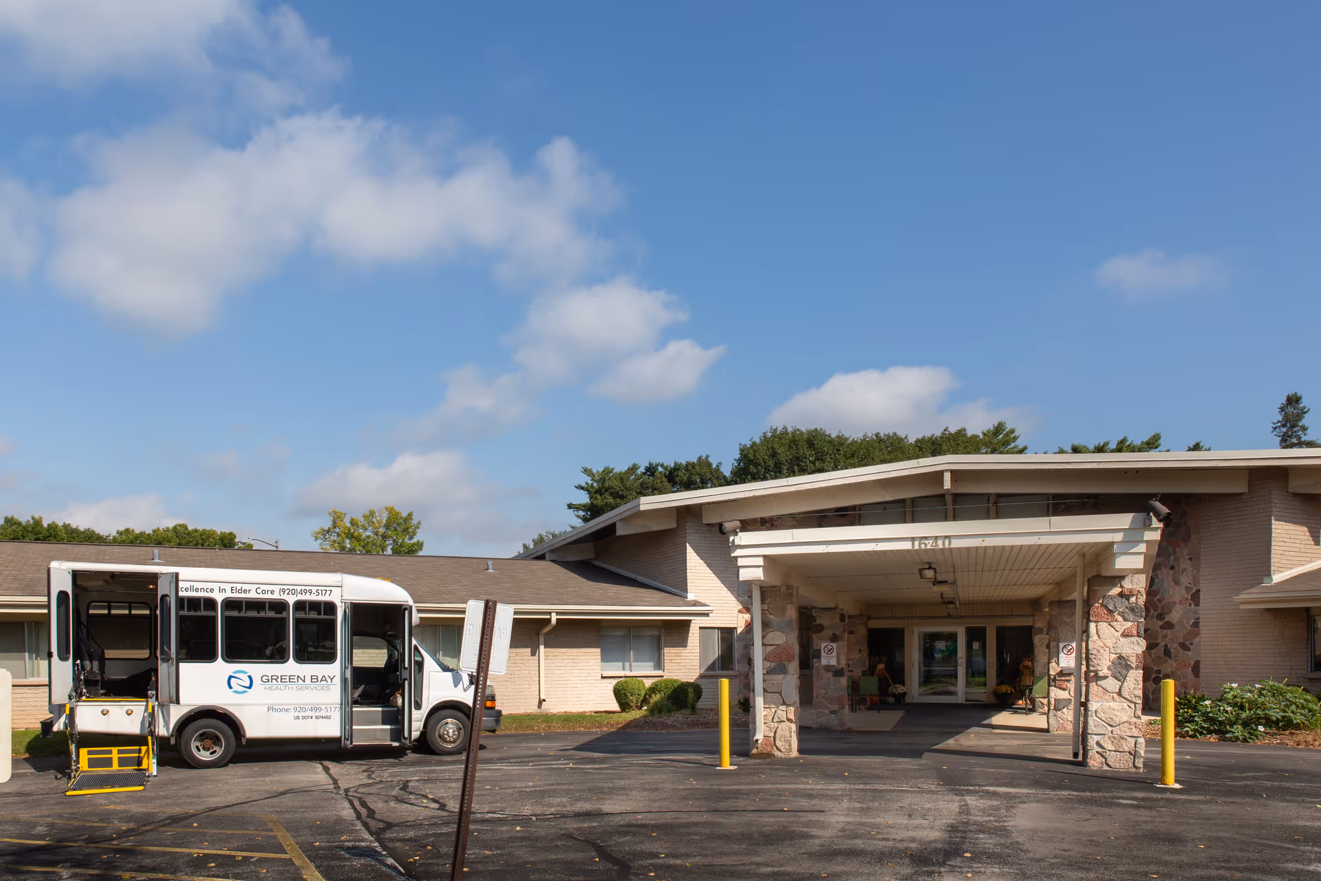 Exterior view of Green Bay Health Services with a white shuttle bus at the front entrance.