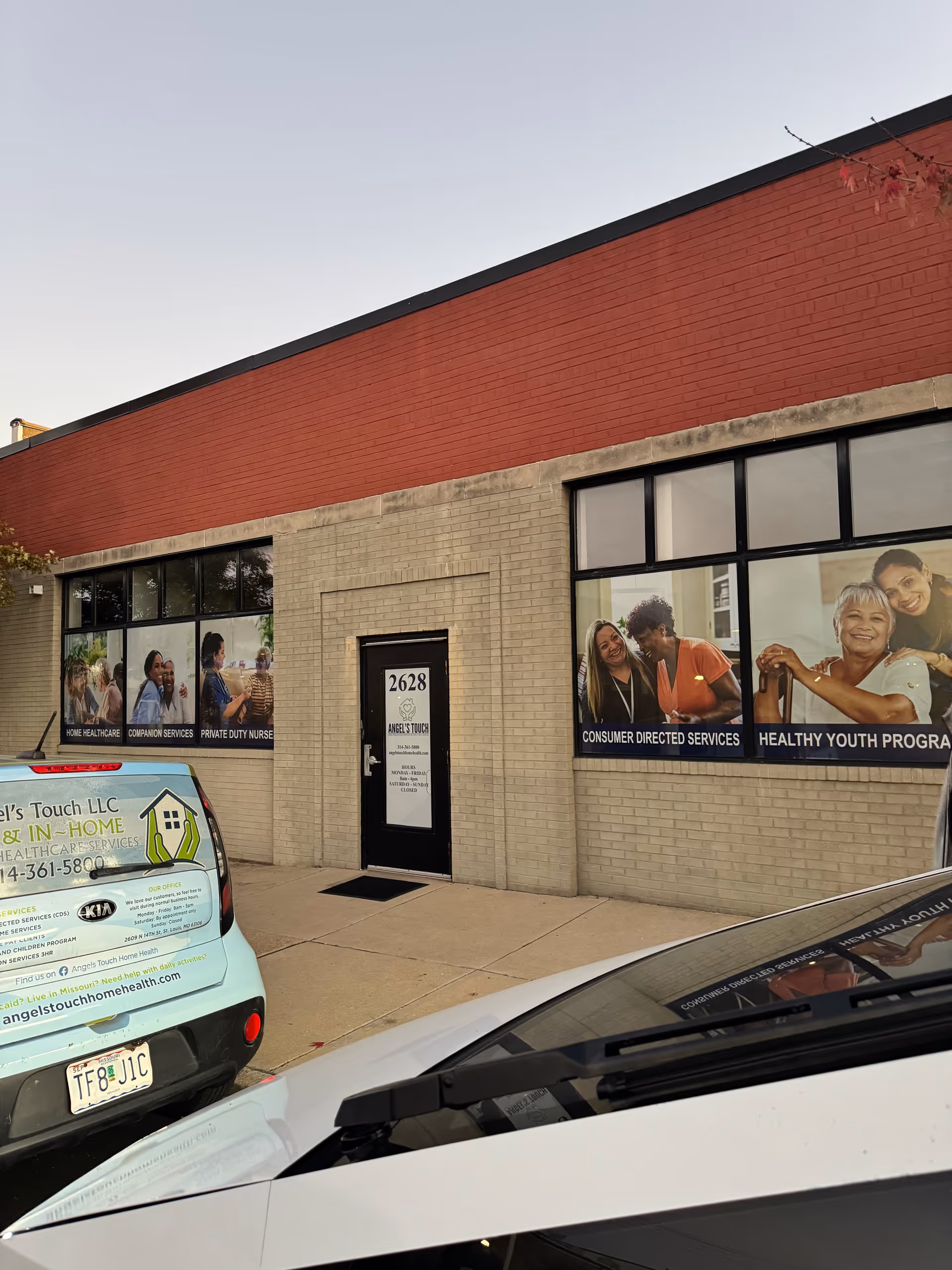 Exterior view of Angel's Touch Home Healthcare building with large window banners and parked cars.