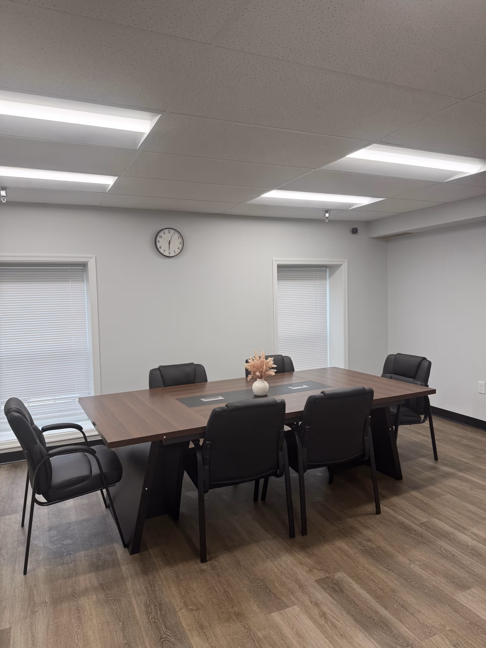 Interior meeting room in a senior facility with a long wooden table and black chairs.