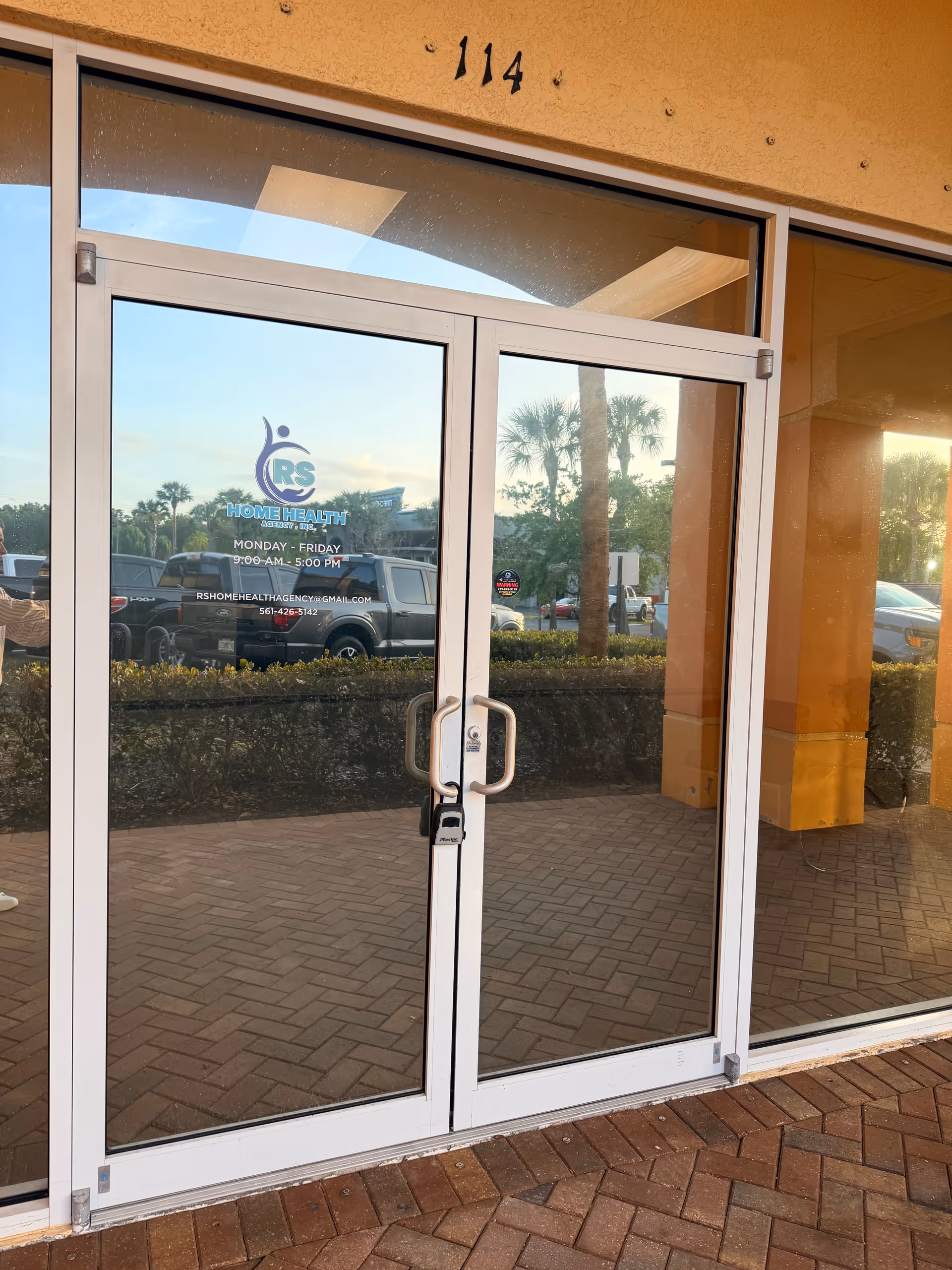 Glass entrance doors at RS Home Health Agency with logo and outdoor parking area.