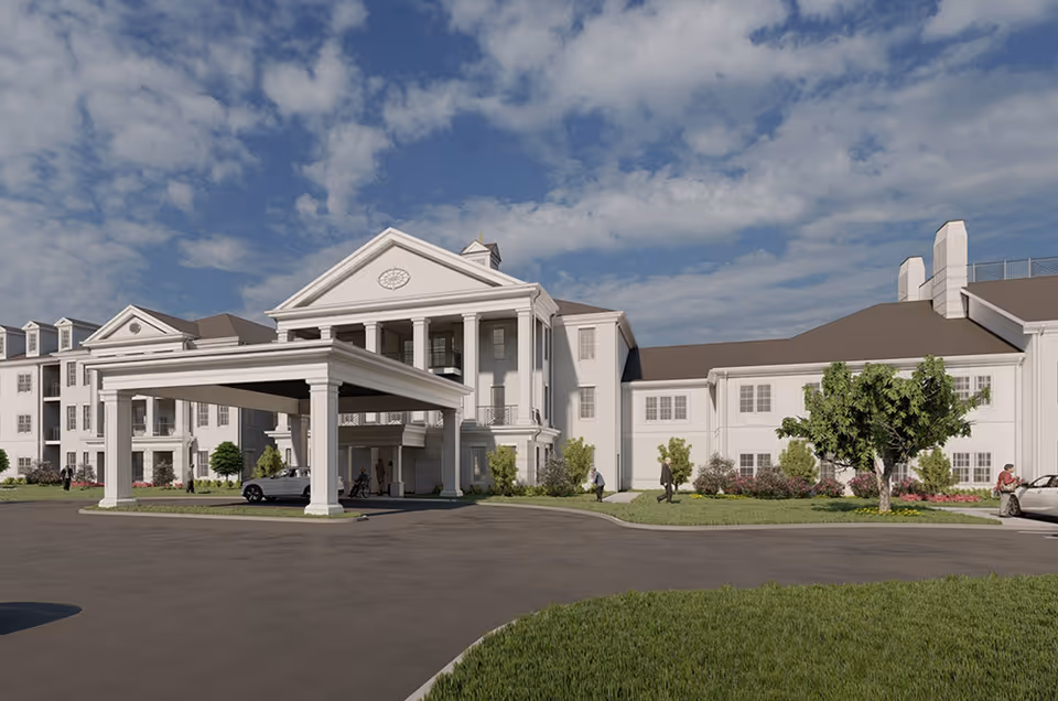 White senior living facility with a porte-cochere entrance and manicured landscaping.
