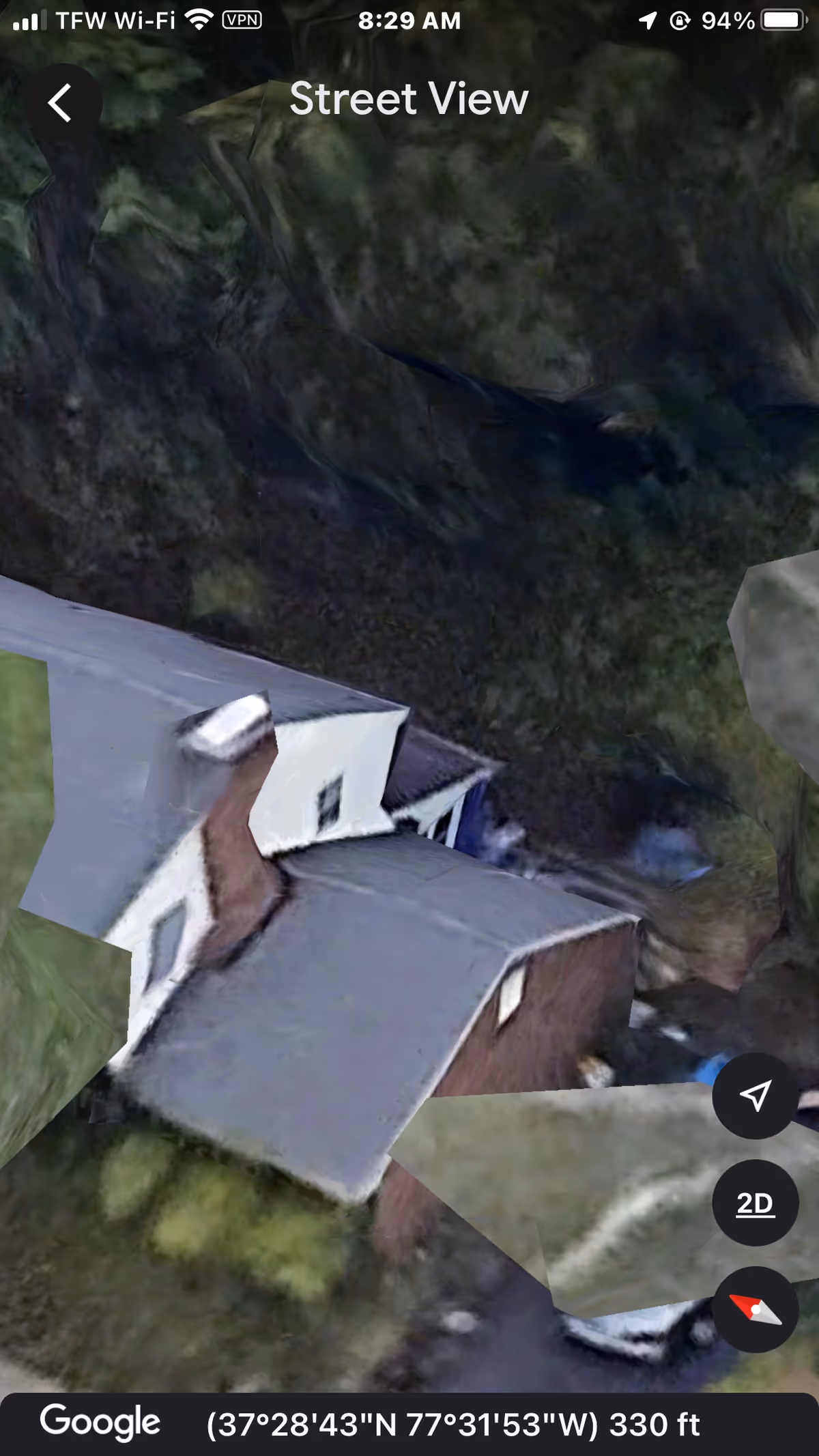 Aerial street view of a residential building surrounded by trees.