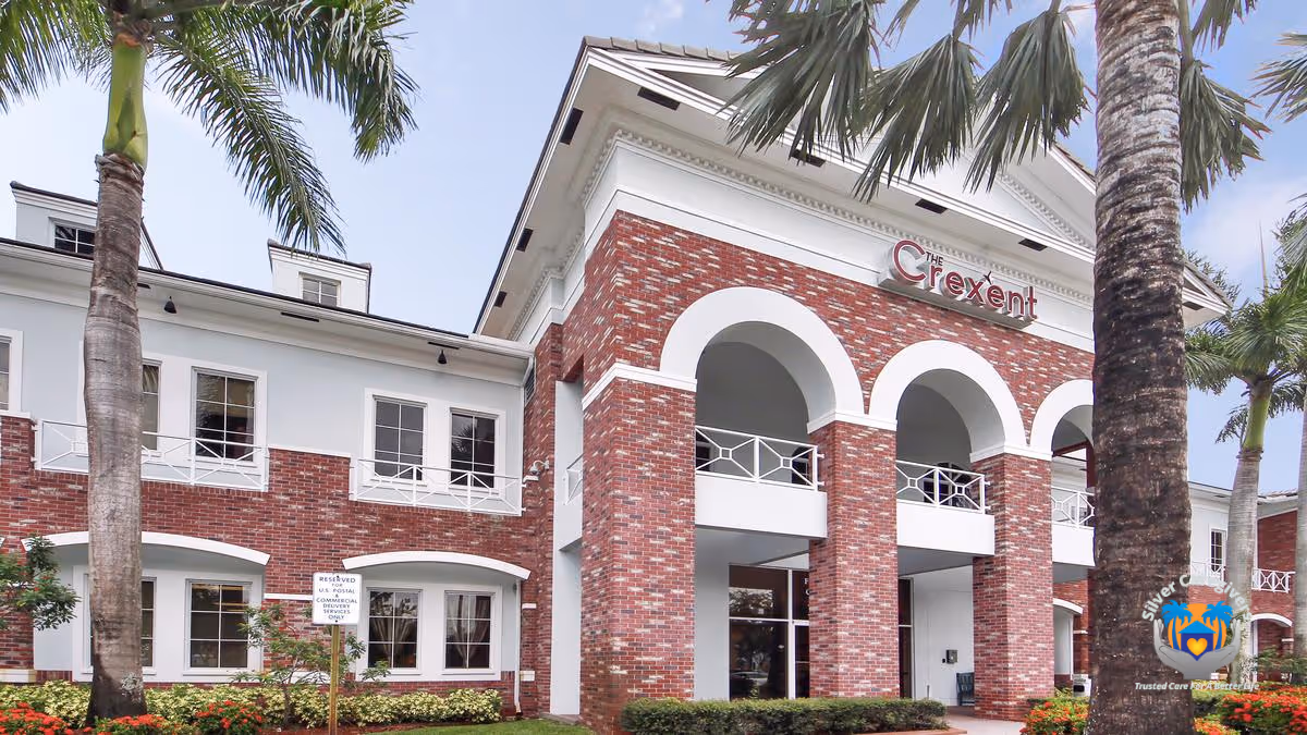Exterior view of a brick senior living building with arches and palm trees.