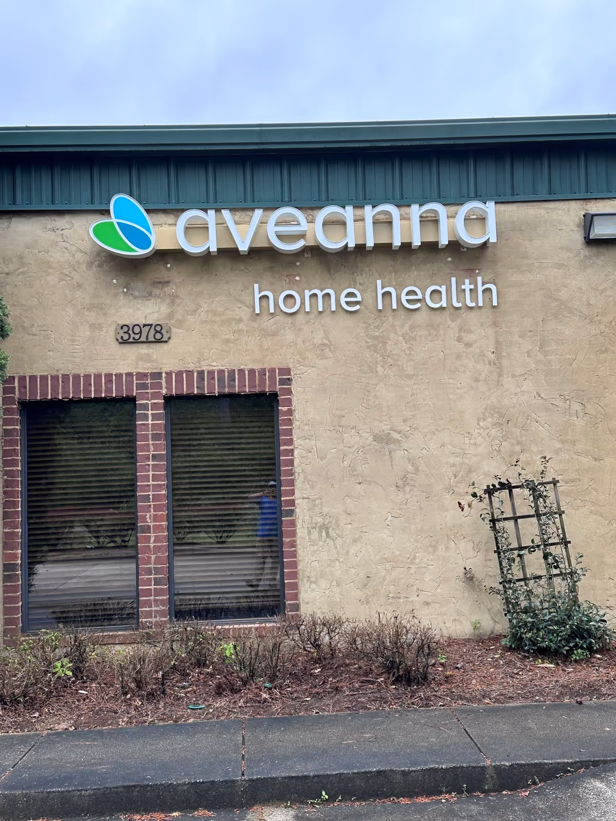 Exterior view of Aveanna Home Health building with sign on beige wall.