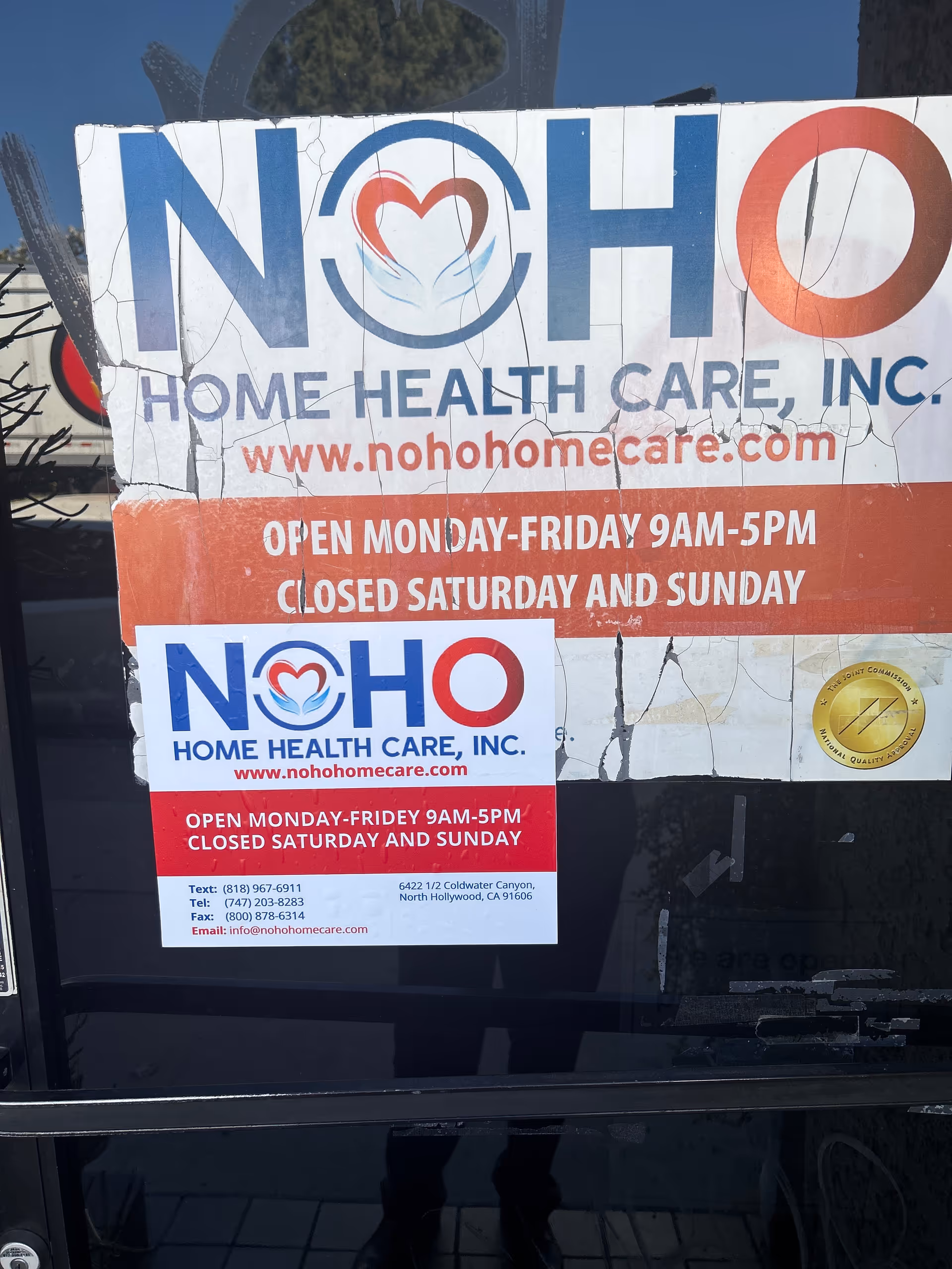 Cracked Noho Home Health Care sign on glass door advertising hours and website.