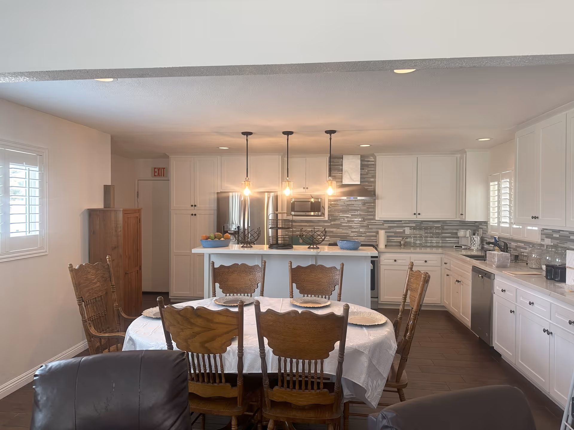 Open concept kitchen and dining area with white cabinets, island, pendant lights, and round table.