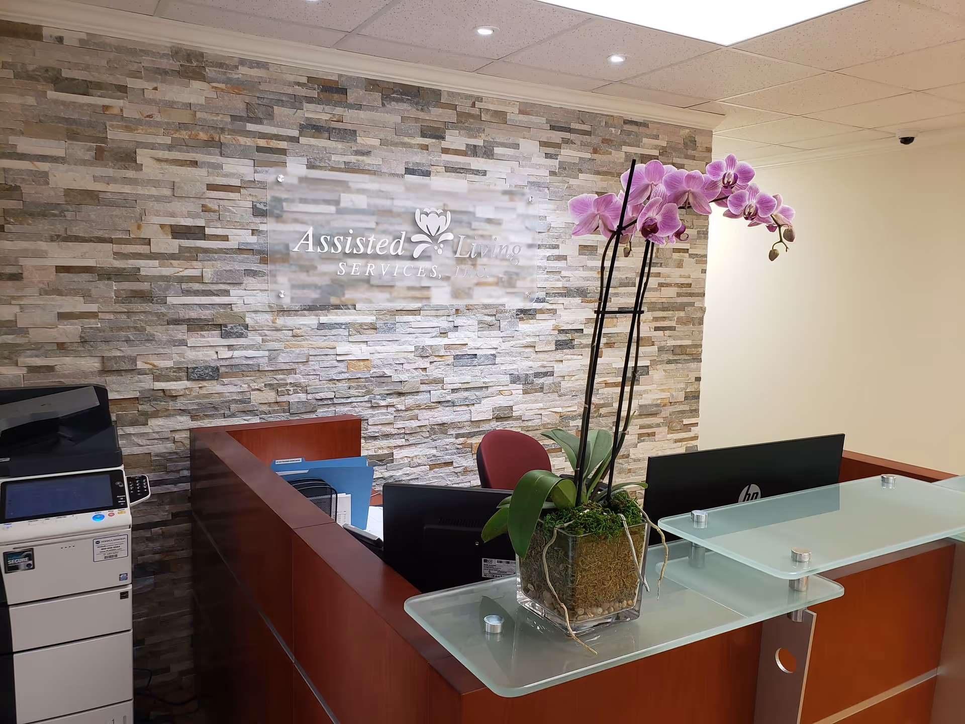 Reception desk in a lobby with stone wall and orchid plant