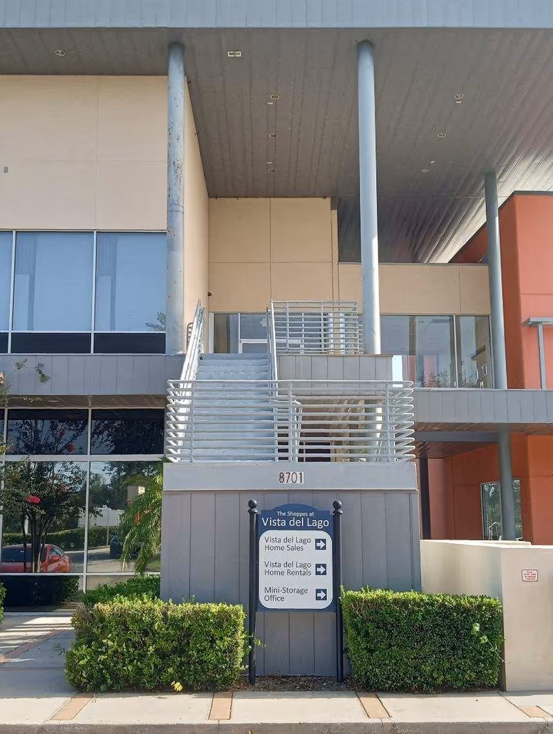 Exterior entrance of a modern building with stairs and Vista del Lago signage.
