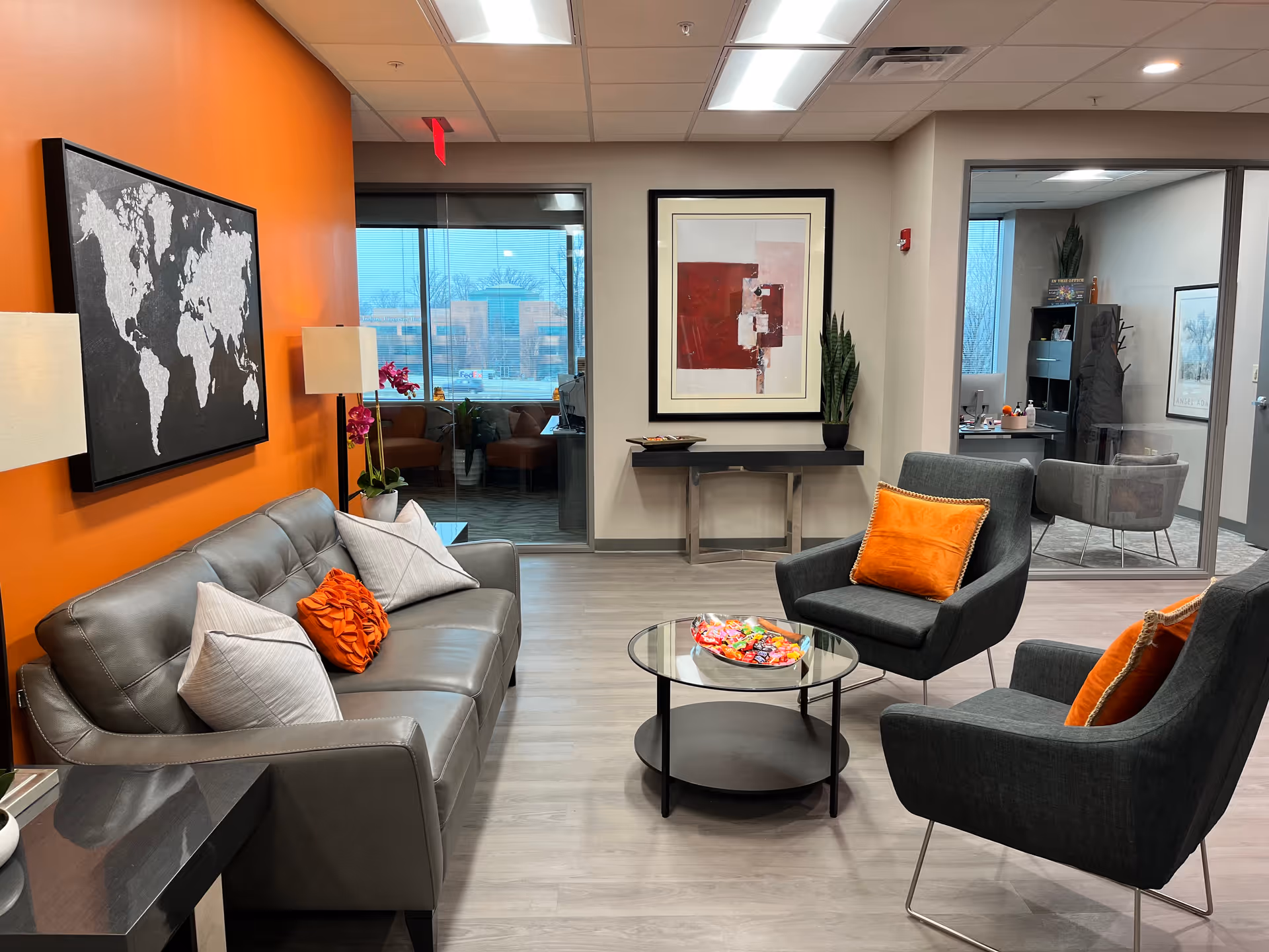 Brighton Hospice Indiana lobby lounge features an orange accent wall, seating, and a glass coffee table.