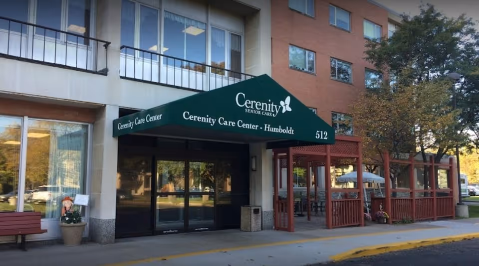 Exterior view of a senior care facility with a green canopy over the entrance.