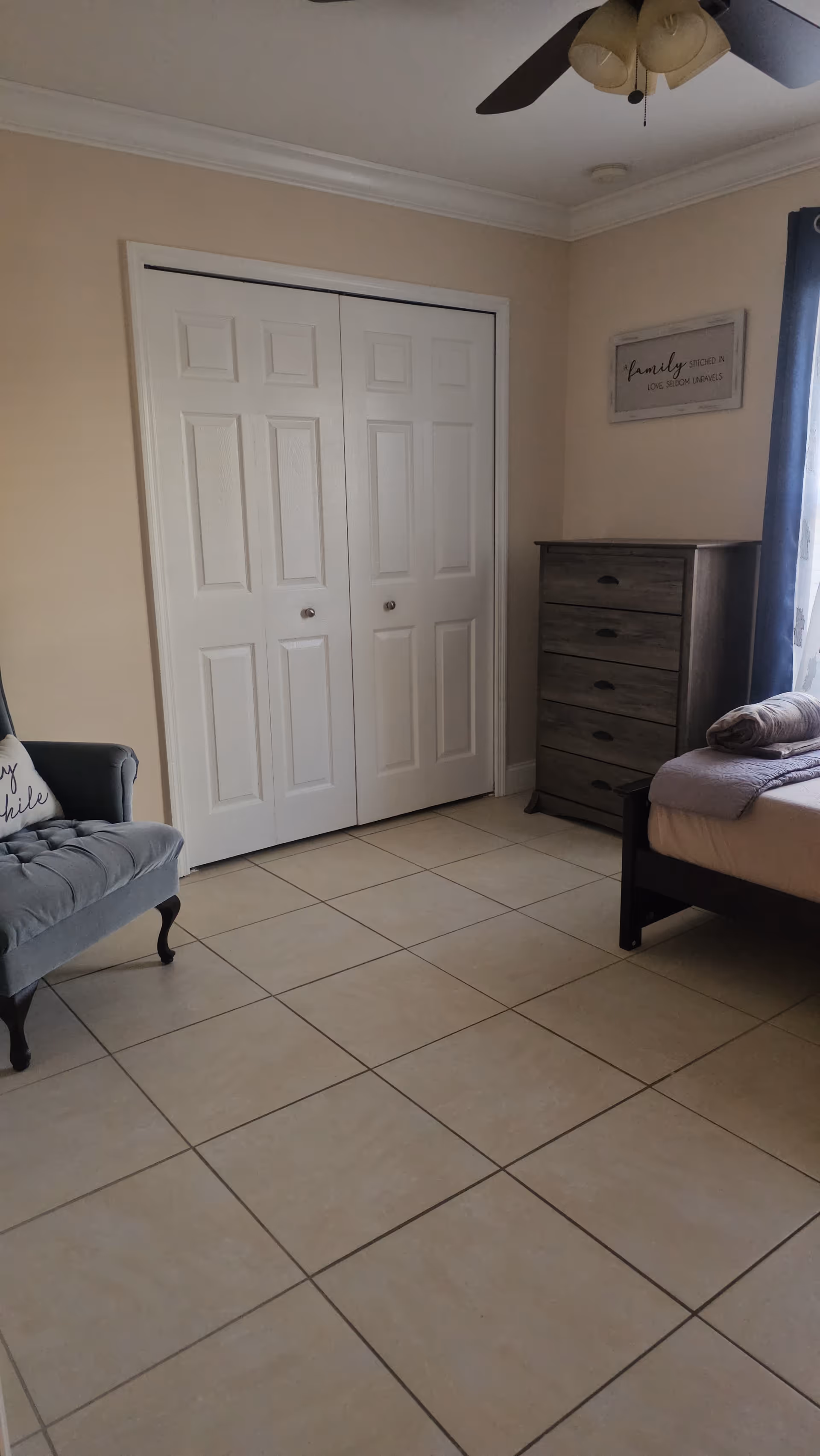 Bedroom in Comfort Homes Assisted Living Facility with bed, dresser, sign, and tiled floor.