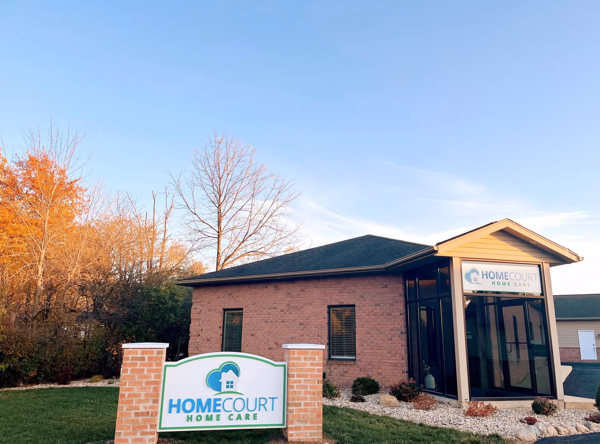 Brick facility with glass entrance and HomeCourt Home Care sign on the front lawn