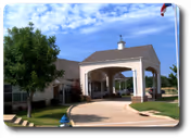 Exterior view of a senior living facility entrance with a covered driveway and trees.