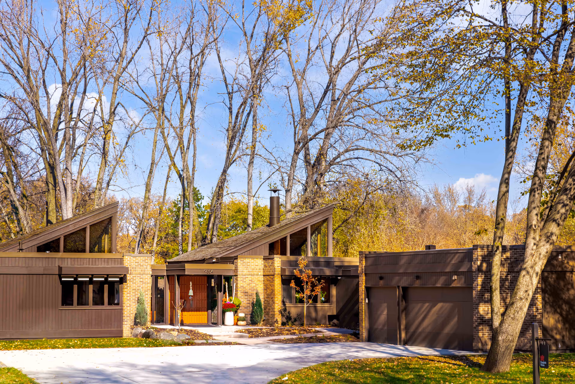 Exterior view of English Rose Suites building with brick, wood accents, and autumn trees.
