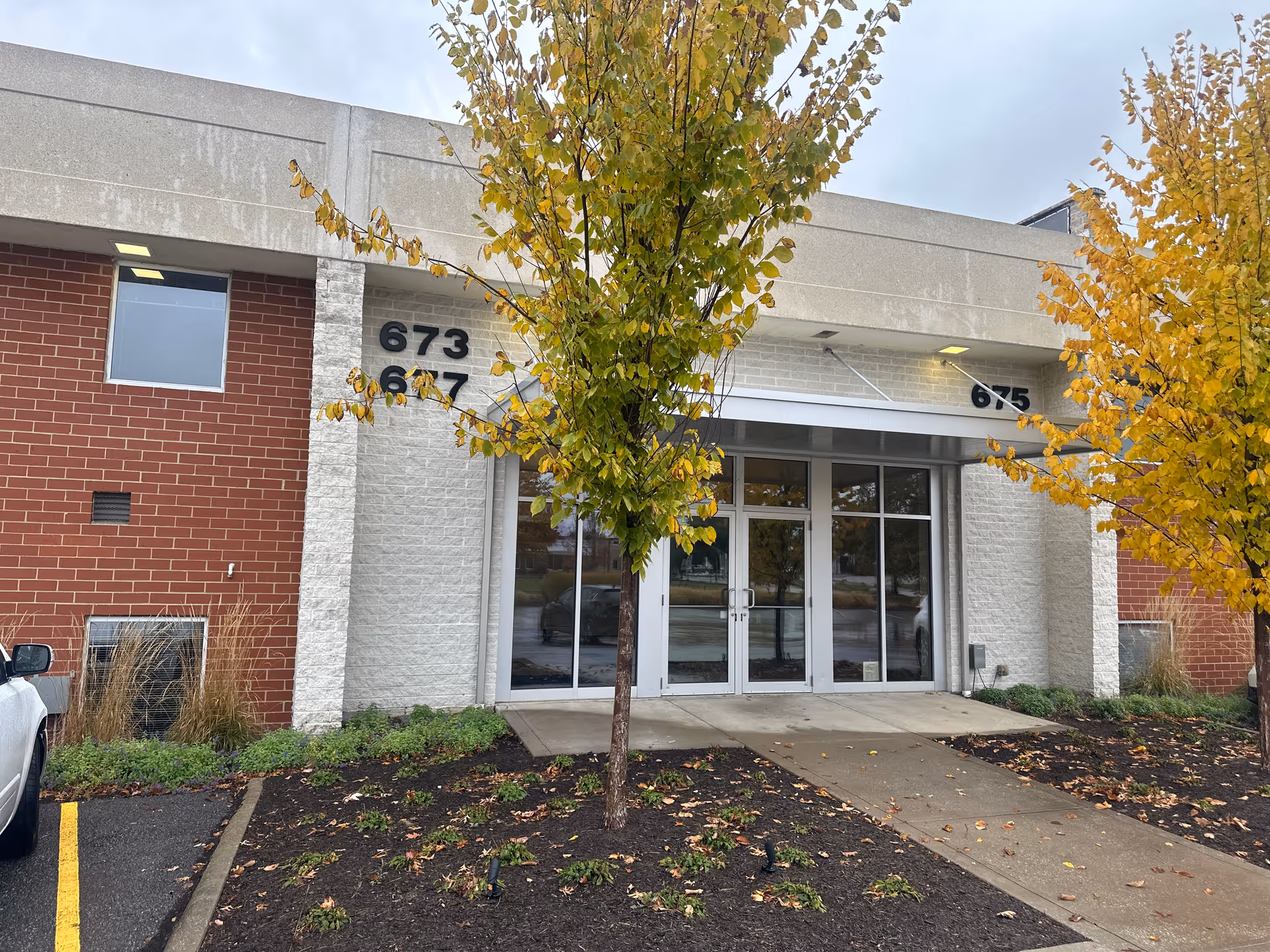 Exterior view of Lizzie’s House Senior Home Care building with glass doors and autumn trees.
